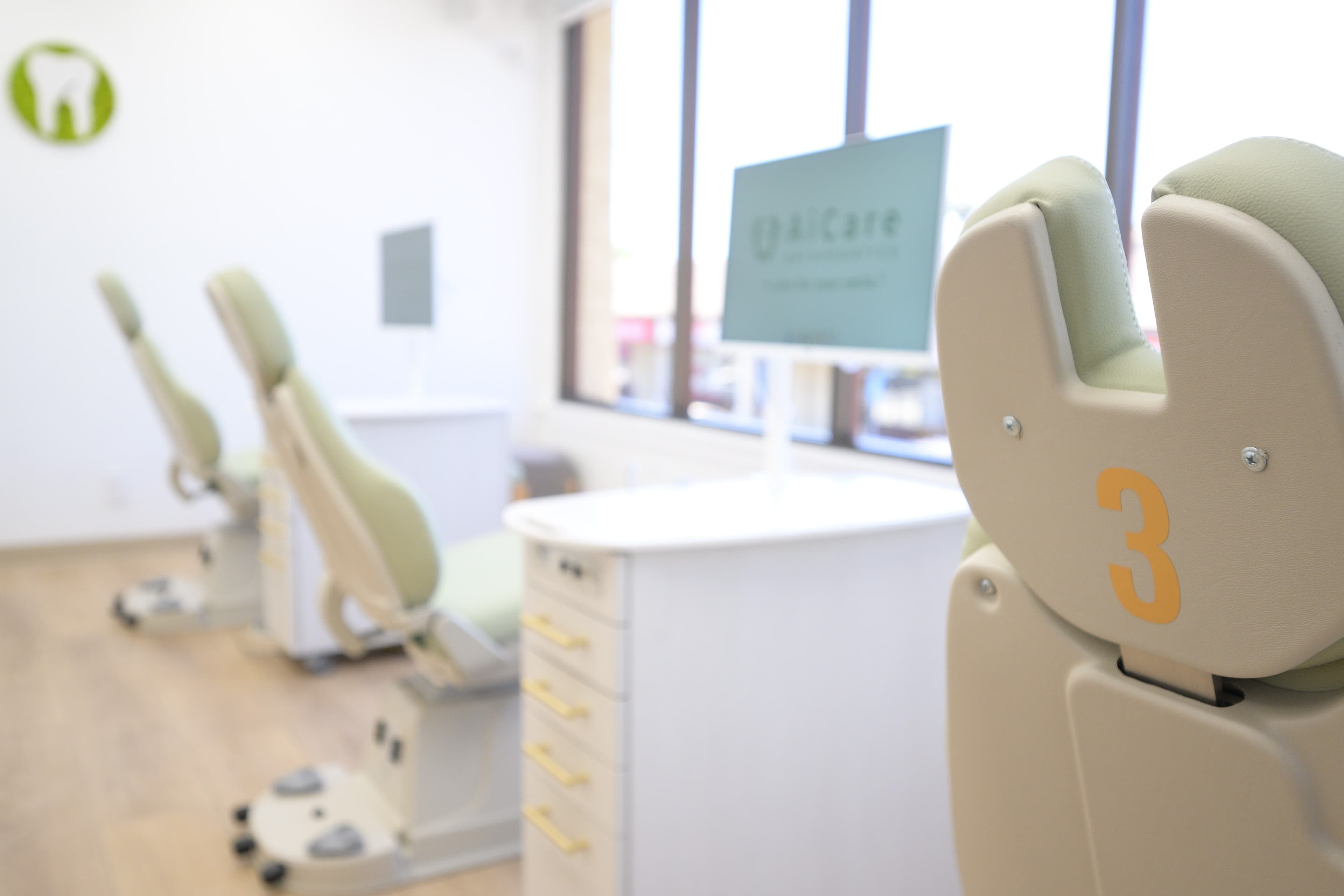 Green orthodontic treatment chairs beside large windows